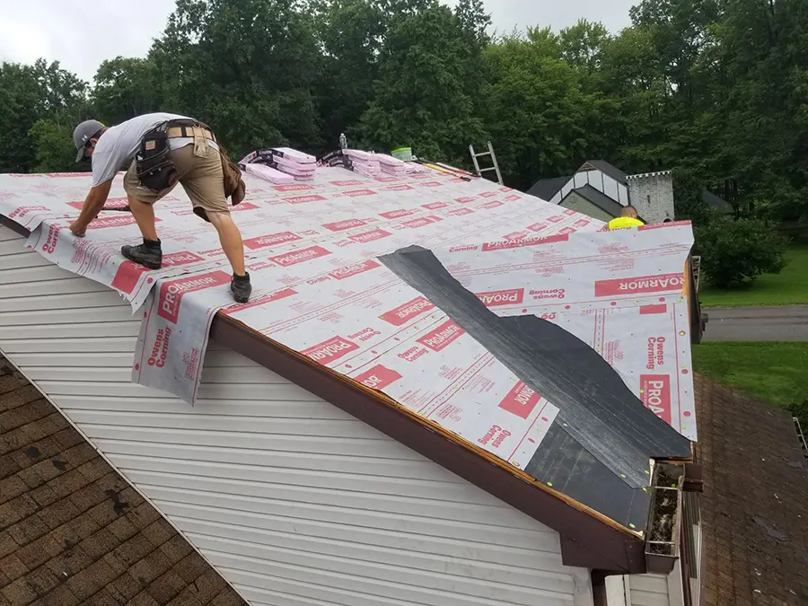roofing contractor working on roof of white home